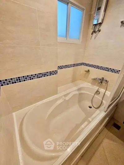 Modern bathroom with bathtub and water heater, featuring stylish tile design.