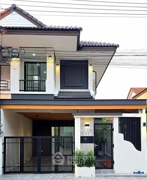 Modern two-story house with sleek design and gated entrance, featuring contemporary architecture and stylish exterior lighting.