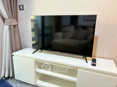 Modern living room with sleek TV on white cabinet and elegant curtains