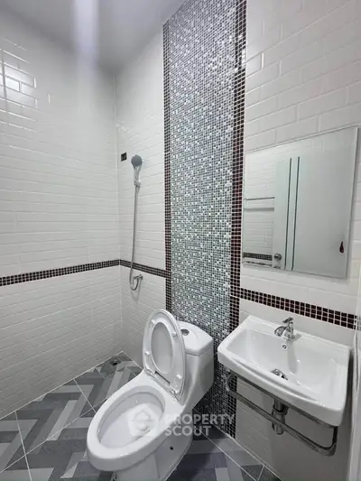 Modern bathroom with sleek white tiles and mosaic accent wall