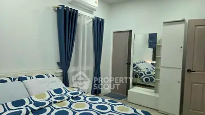 Cozy bedroom with modern decor and ample natural light, featuring stylish blue curtains and patterned bedding.