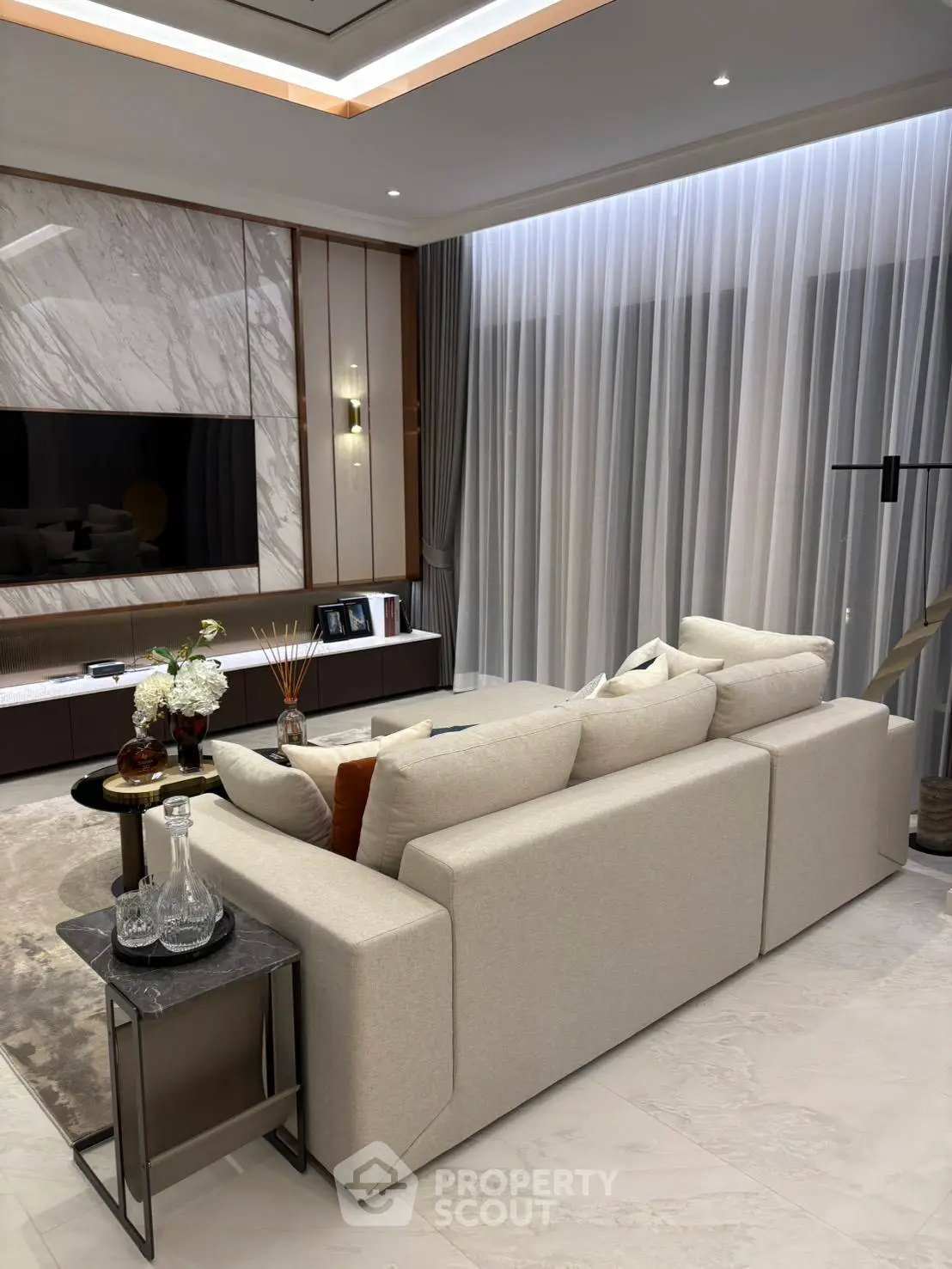 Luxurious modern living room with elegant decor and large TV, perfect for relaxation and entertainment.