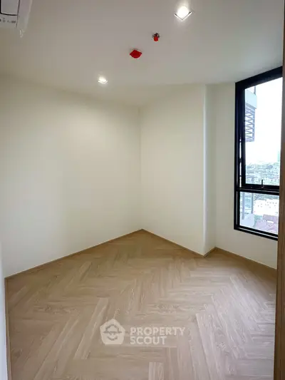 Spacious empty room with large window and wooden flooring, perfect for customization.