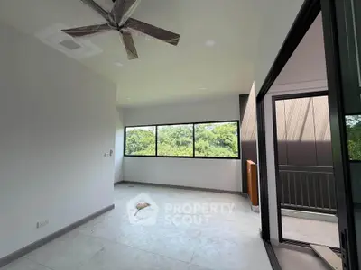 Spacious room with large windows and balcony overlooking lush greenery, perfect for serene living.