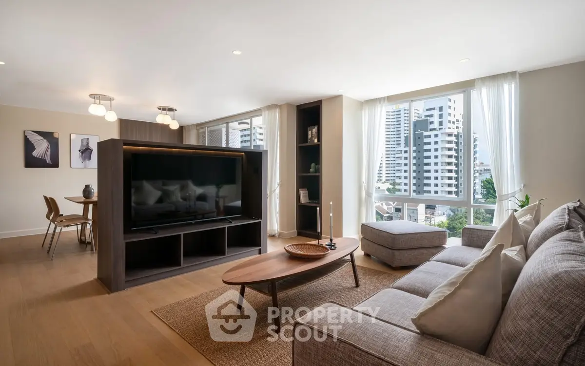 Spacious modern living room with large windows and city view, featuring stylish furniture and open layout.