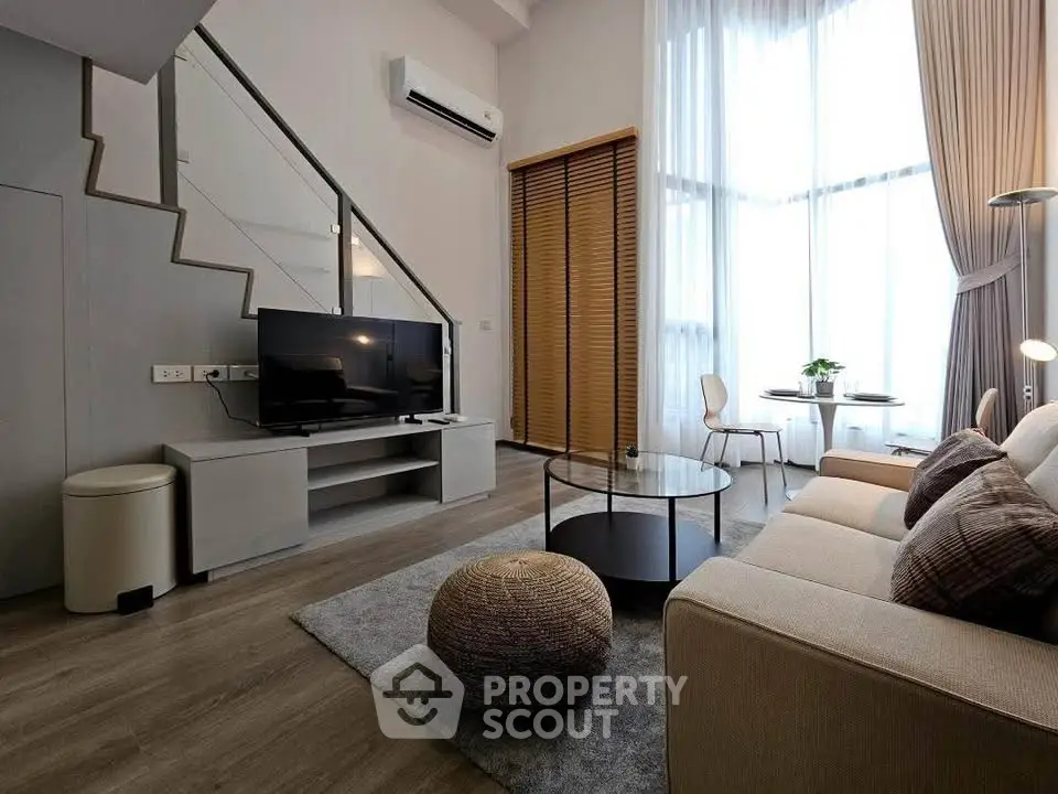 Modern living room with high ceilings, large windows, and stylish decor in a contemporary apartment.