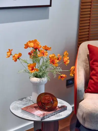 Chic living room corner with vibrant orange flowers and cozy decor accents.