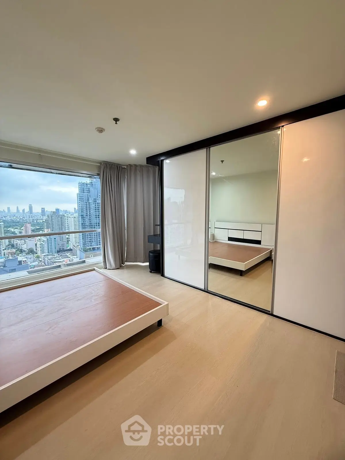 Spacious bedroom with stunning city view and large mirrored closet.