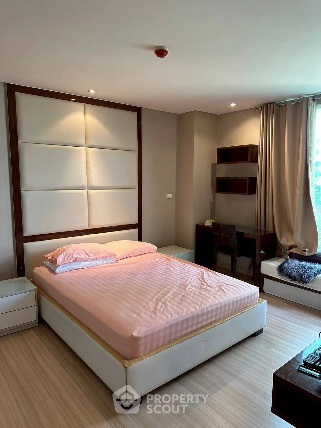 Spacious bedroom with modern decor and natural light, featuring a comfortable bed and stylish workspace.