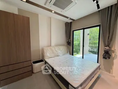 Modern bedroom with large window and garden view, featuring a comfortable bed and stylish wardrobe.