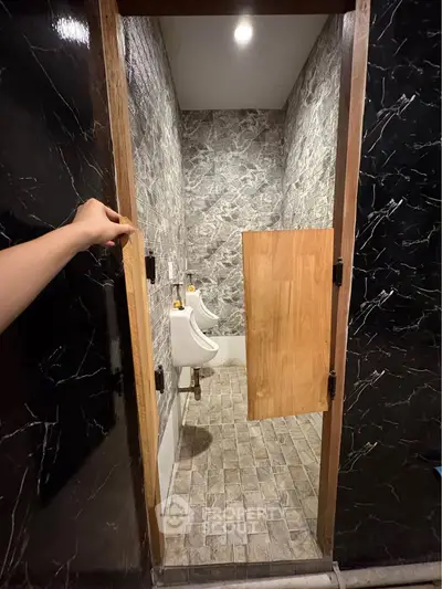Unique bathroom with marble walls and urinals, featuring a half-door entrance.