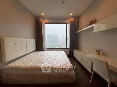 Modern bedroom with large window offering city view, featuring sleek furniture and neutral tones.