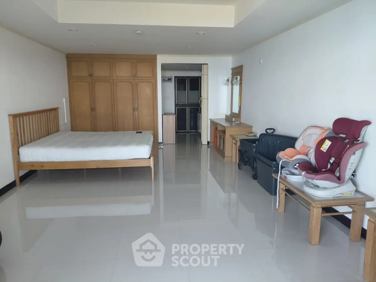 Spacious bedroom with wooden furniture and glossy tiled floor, ideal for modern living.
