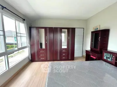 Spacious bedroom with large windows and elegant wooden furniture