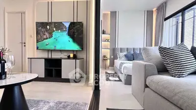 Modern living room with stylish decor and large TV, adjacent to cozy bedroom.