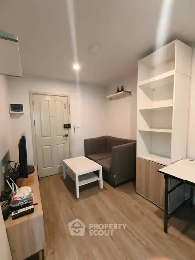 Cozy living room with modern furniture and wooden flooring in a compact apartment.