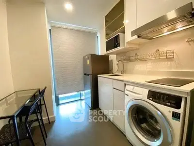 Modern kitchen with washing machine, fridge, and dining area in sleek apartment.