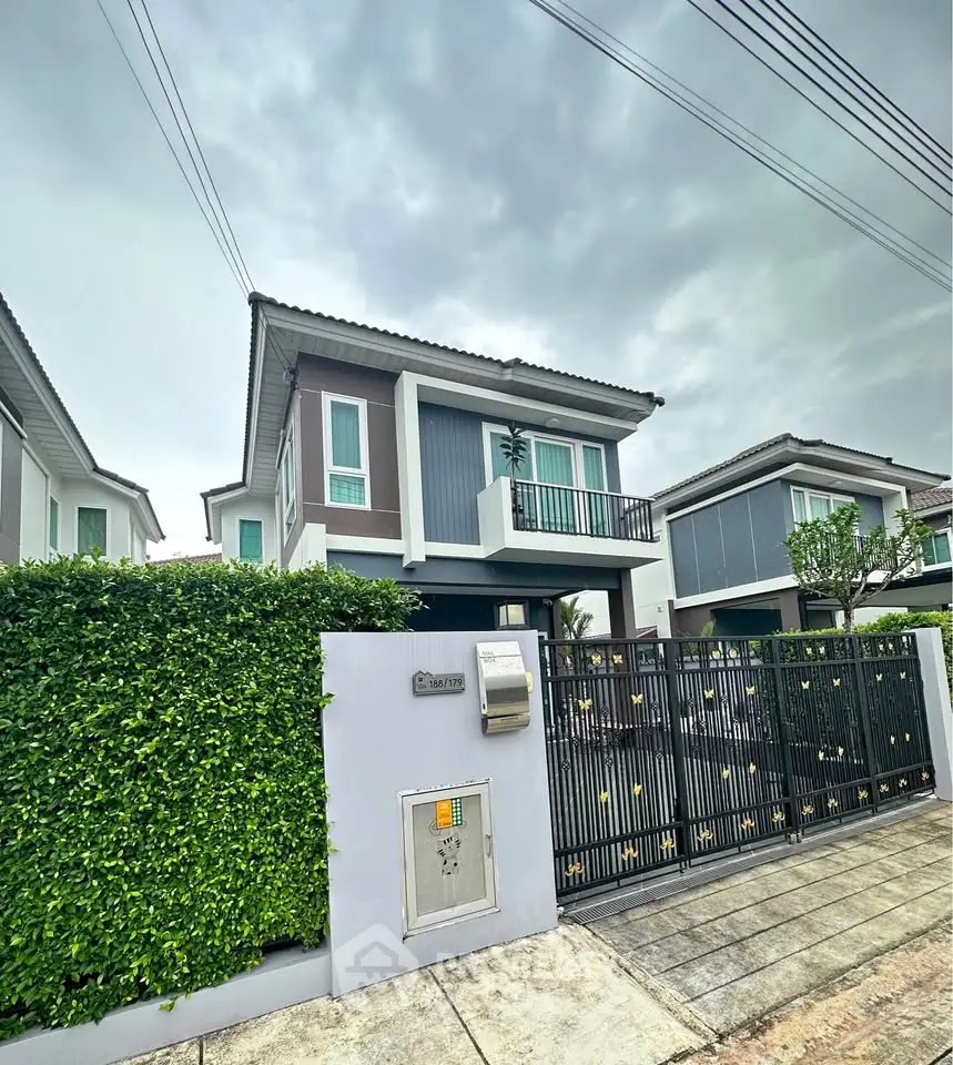 Modern two-story house with gated entrance and lush greenery