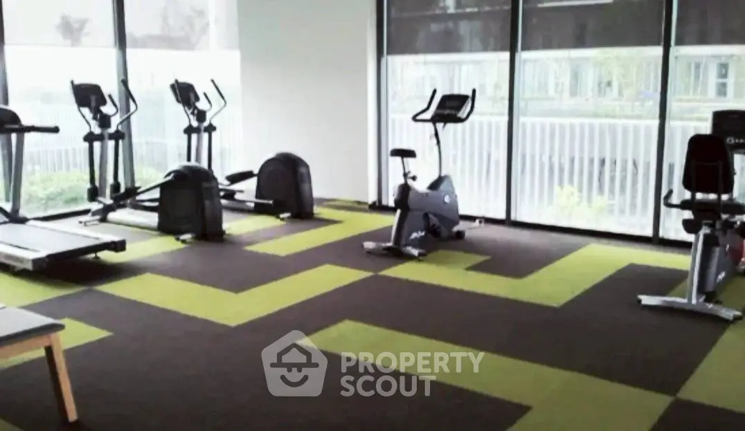 Modern gym with exercise equipment and large windows in a residential building.