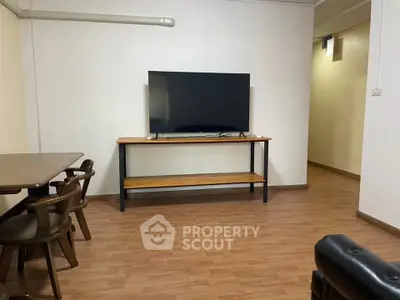 Spacious living room with modern TV setup and wooden flooring