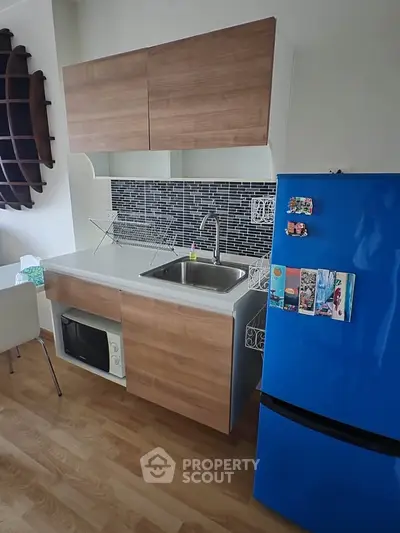 Modern kitchen with blue fridge, wood cabinets, and sleek backsplash