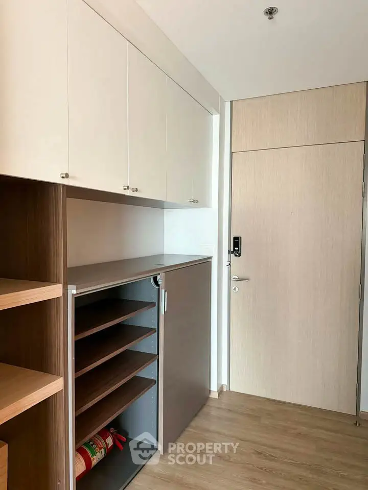 Modern storage area with sleek cabinets and wooden shelves in a contemporary apartment.