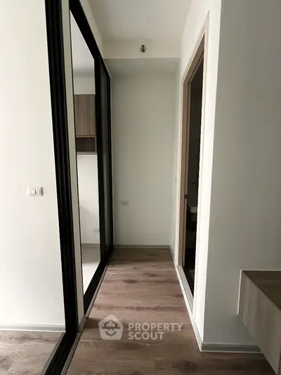 Modern apartment hallway with wooden flooring and sliding mirror doors