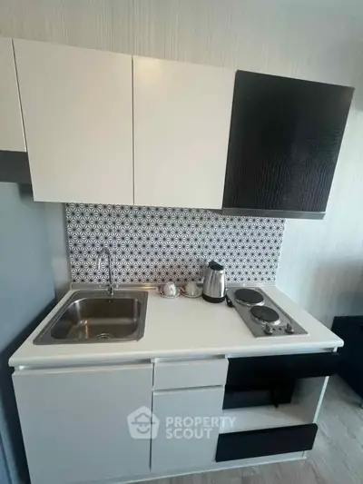 Modern compact kitchen with sleek cabinetry and electric stove, perfect for urban living.