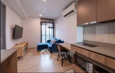 Modern living room with sleek kitchen, featuring a cozy blue sofa and wall-mounted TV, perfect for urban living.