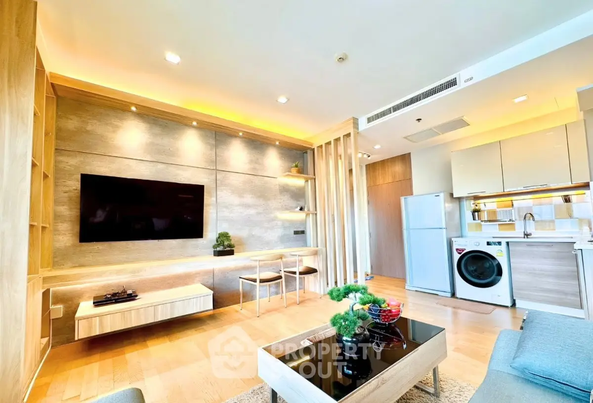 Modern living room with open kitchen, featuring sleek design and integrated appliances.