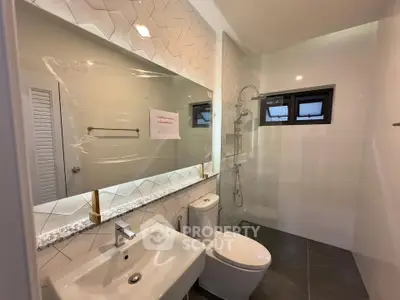 Modern bathroom with sleek fixtures and large mirror in a contemporary home.