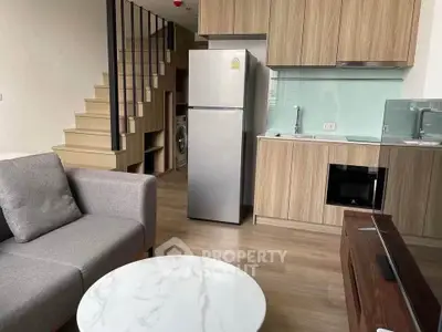 Modern loft apartment with stylish kitchen and cozy living area, featuring wooden cabinetry and sleek appliances.