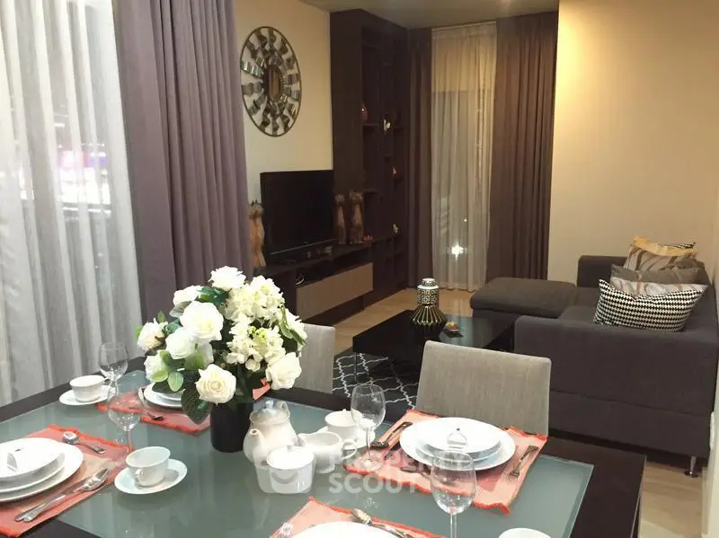 Elegant living room with modern decor and dining area, featuring a cozy sofa and stylish table setting.