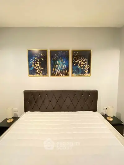 Elegant bedroom with modern decor and stylish artwork above a plush bed.