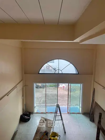Spacious interior with high ceiling and large window, ideal for natural light.