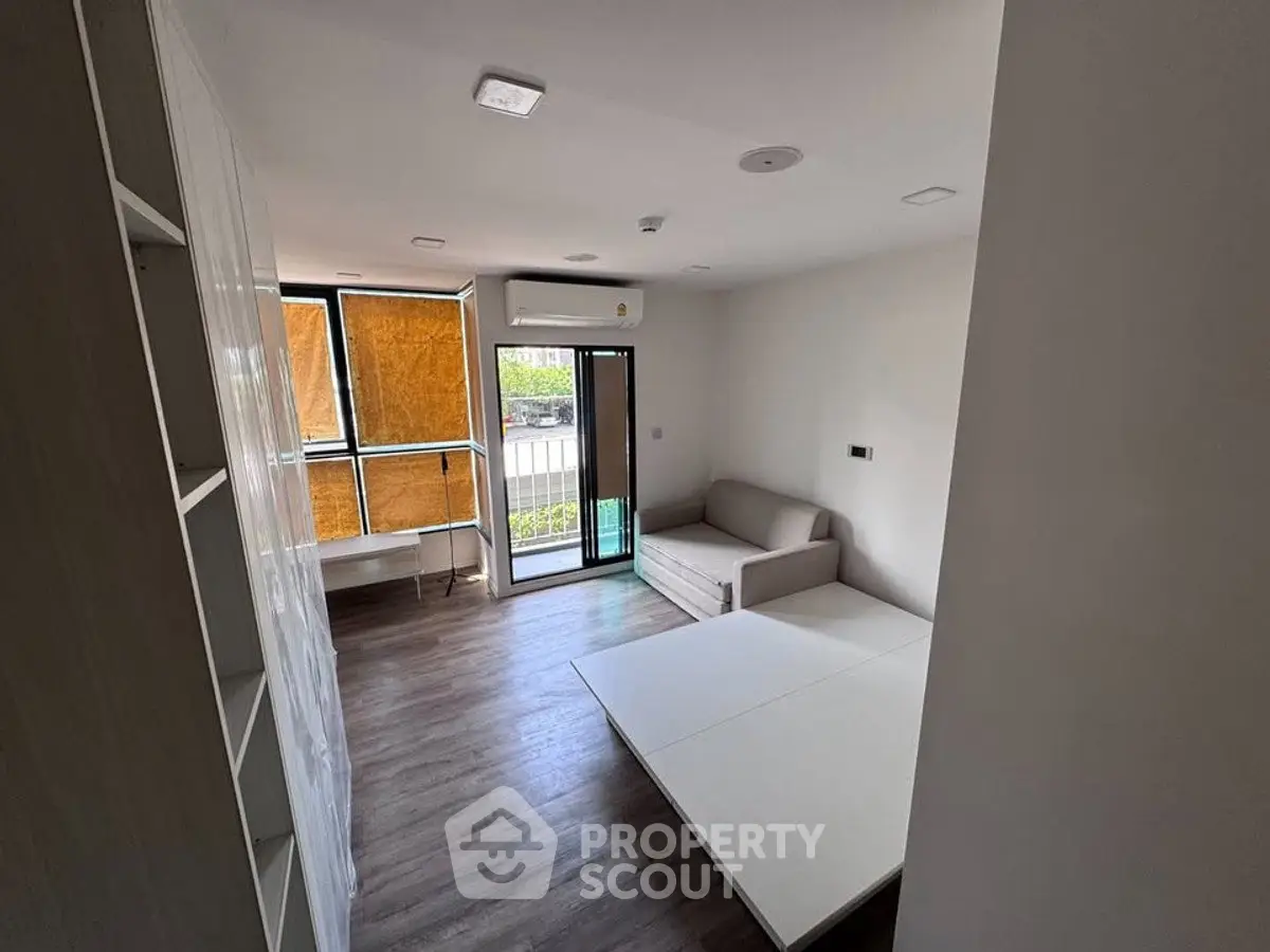 Modern living room with sleek design, featuring a sofa, air conditioning, and large windows for natural light.