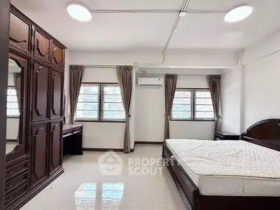 Spacious bedroom with elegant wooden furniture and large windows for natural light.