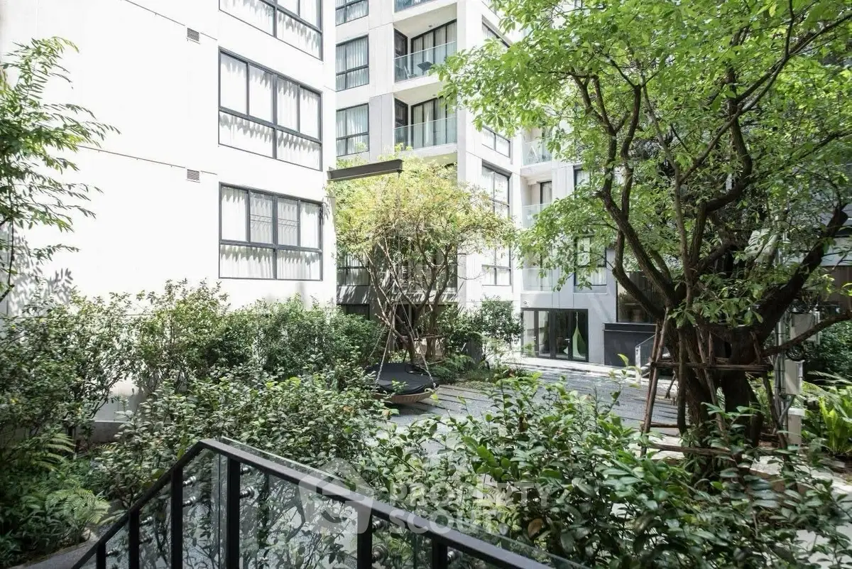 Modern apartment building with lush garden view and large windows.