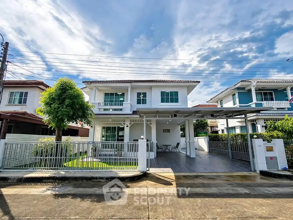 Charming two-story house with spacious driveway and lush greenery under a bright blue sky.