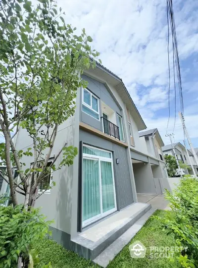 Modern two-story house with lush garden and clear blue sky