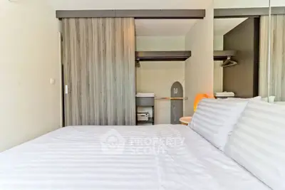Modern bedroom with striped bedding and sliding closet doors in a stylish apartment.