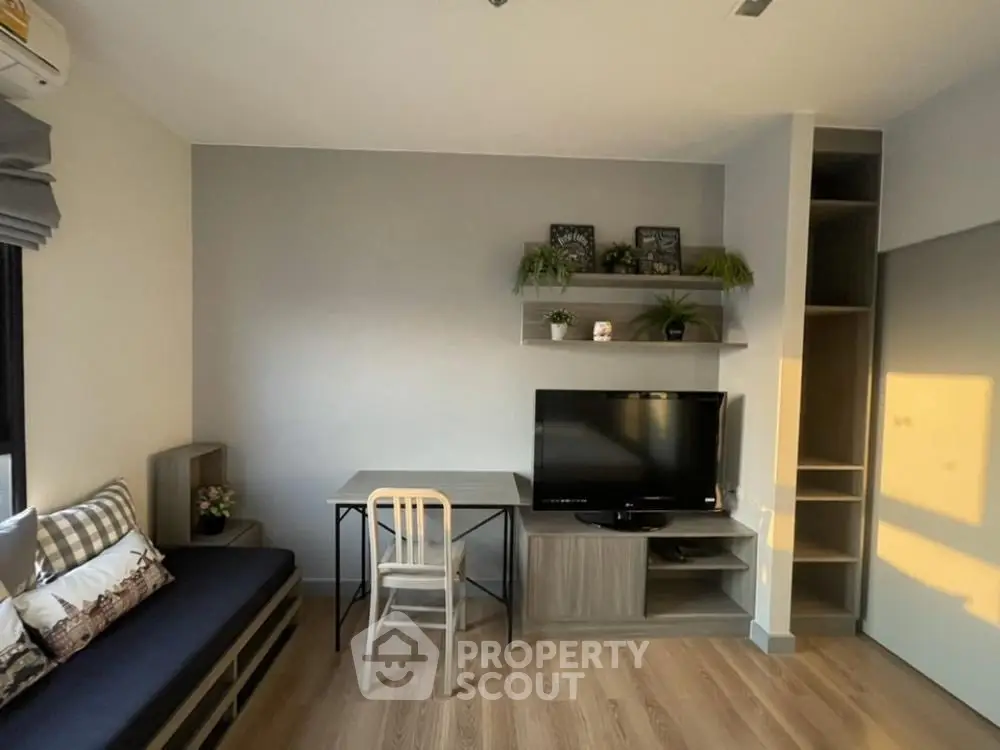 Modern living room with stylish decor and natural light, featuring a cozy seating area and sleek TV setup.