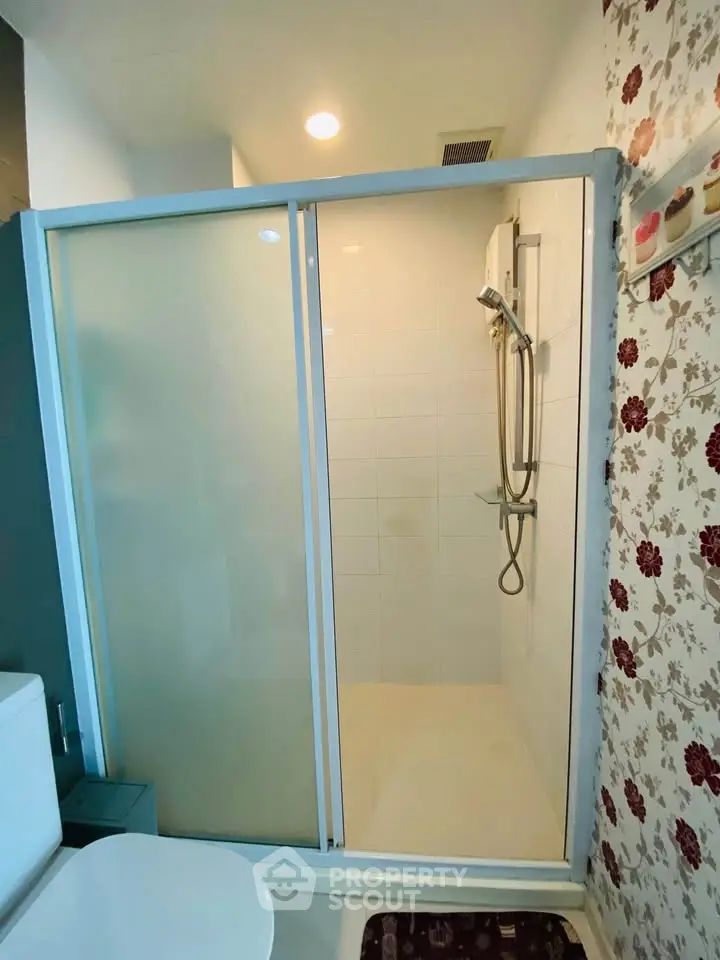 Modern bathroom with sleek shower enclosure and floral wallpaper accent.