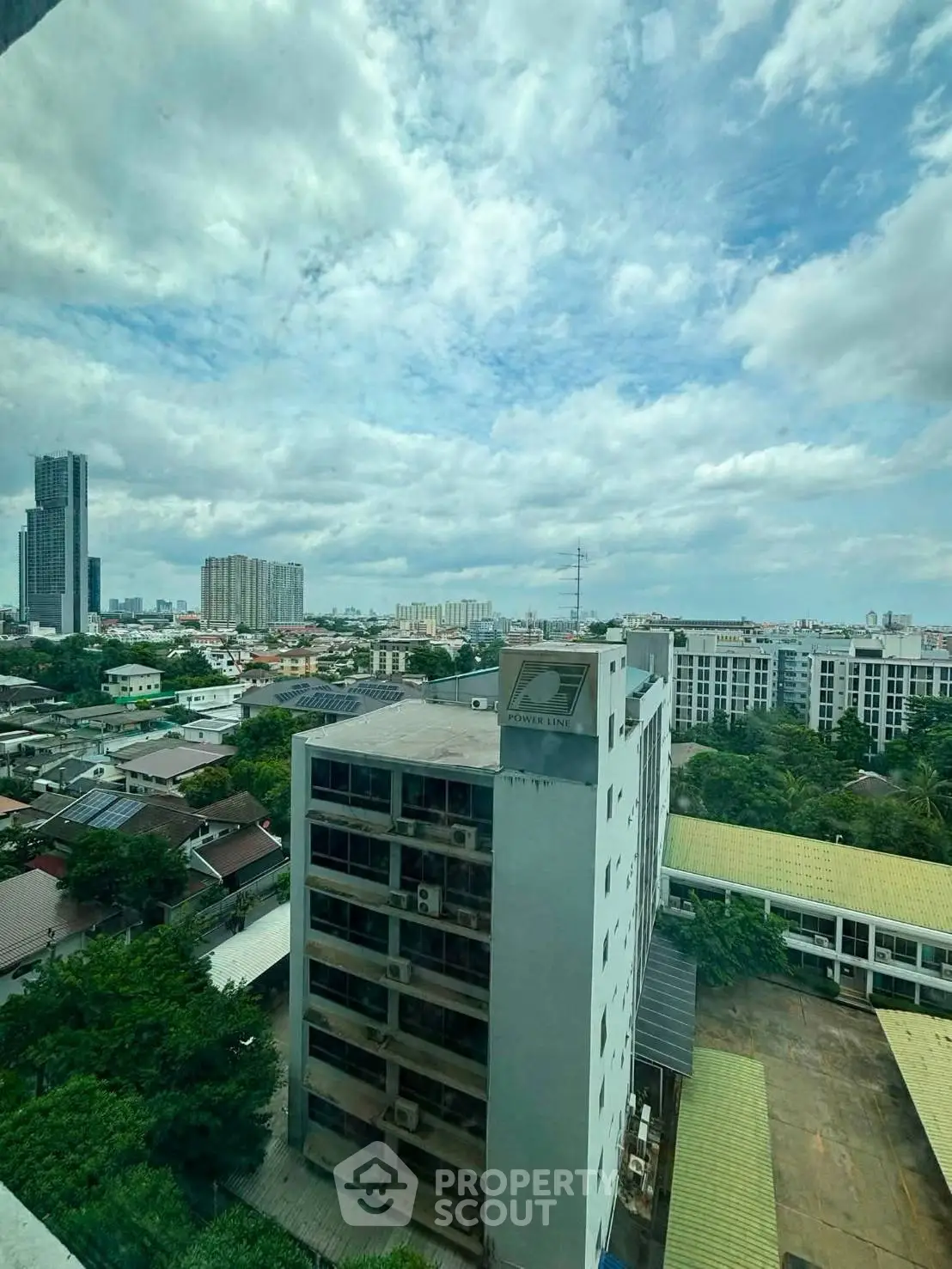 Stunning cityscape view from high-rise building window showcasing urban skyline and lush greenery.