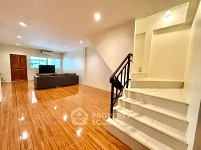 Spacious living room with modern staircase and wooden flooring, perfect for family gatherings.