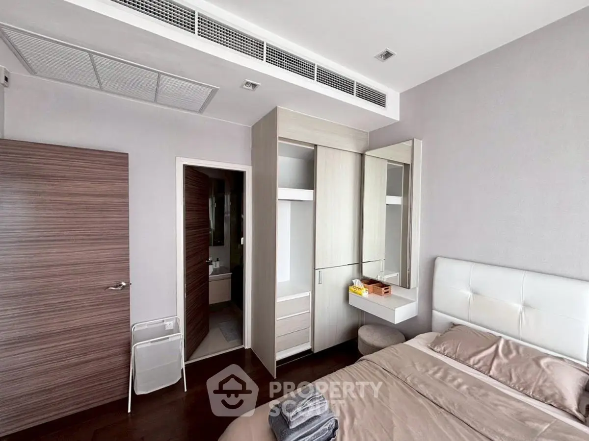 Modern bedroom with sleek furniture and ensuite bathroom in a stylish apartment.