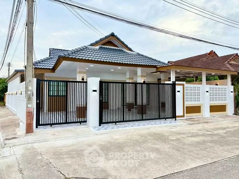 Charming single-story house with modern gate and tiled roof in suburban neighborhood.