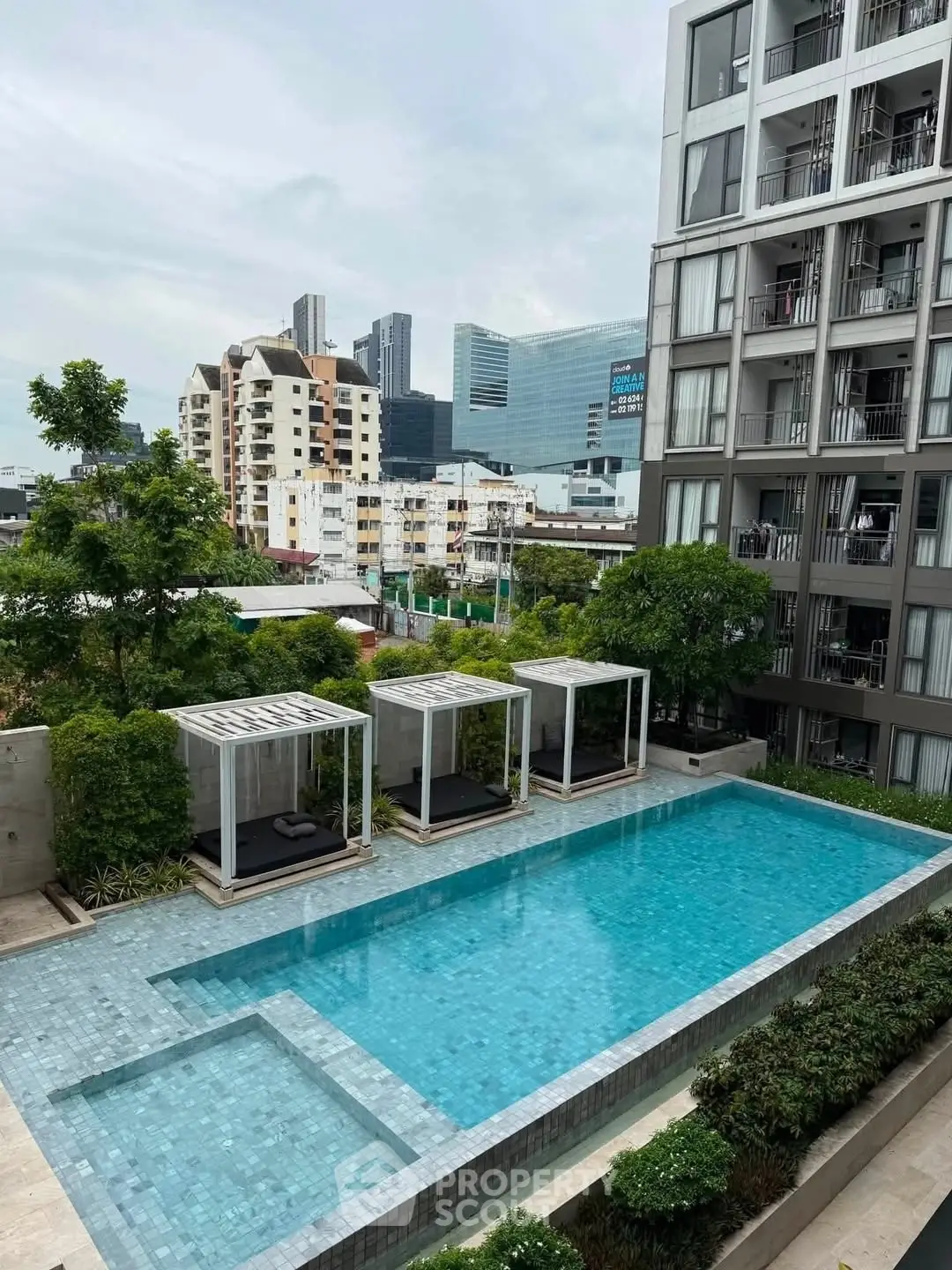 Modern apartment building with a luxurious outdoor pool and city skyline view.