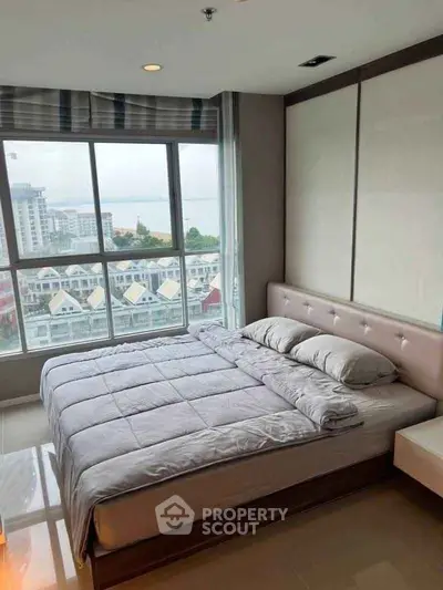 Modern bedroom with large window offering stunning city and sea view, featuring a cozy bed and elegant decor.