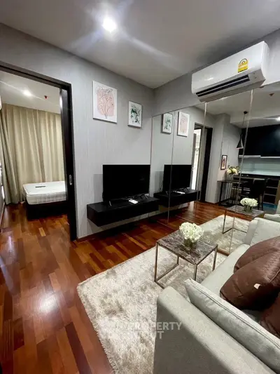 Modern living room with hardwood floors, cozy sofa, and wall-mounted TV in stylish apartment.